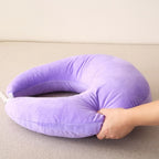 Coussin de lecture en C violet posé à plat, une main presse son extrémité