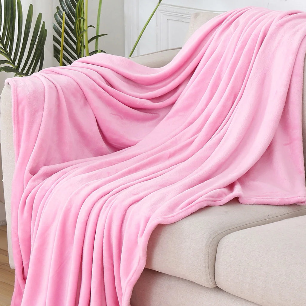 Plaid polaire uni rose drapé sur un canapé crème