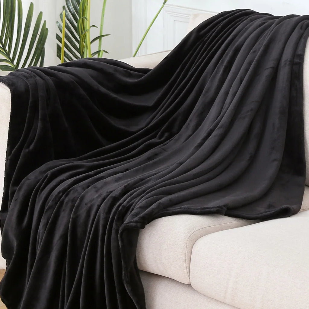 Plaid polaire uni noir drapé sur un canapé crème