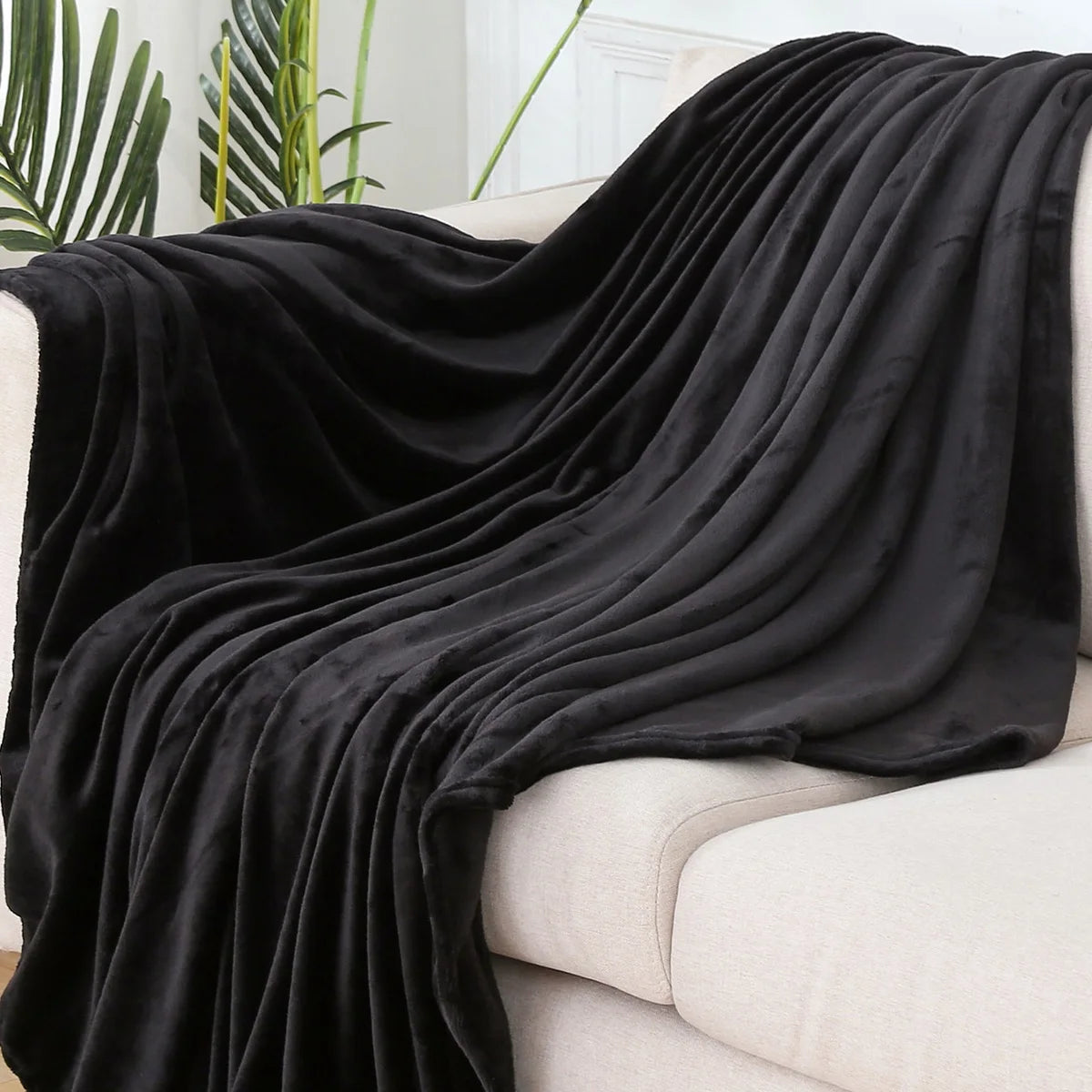 Plaid polaire uni noir drapé sur un canapé crème