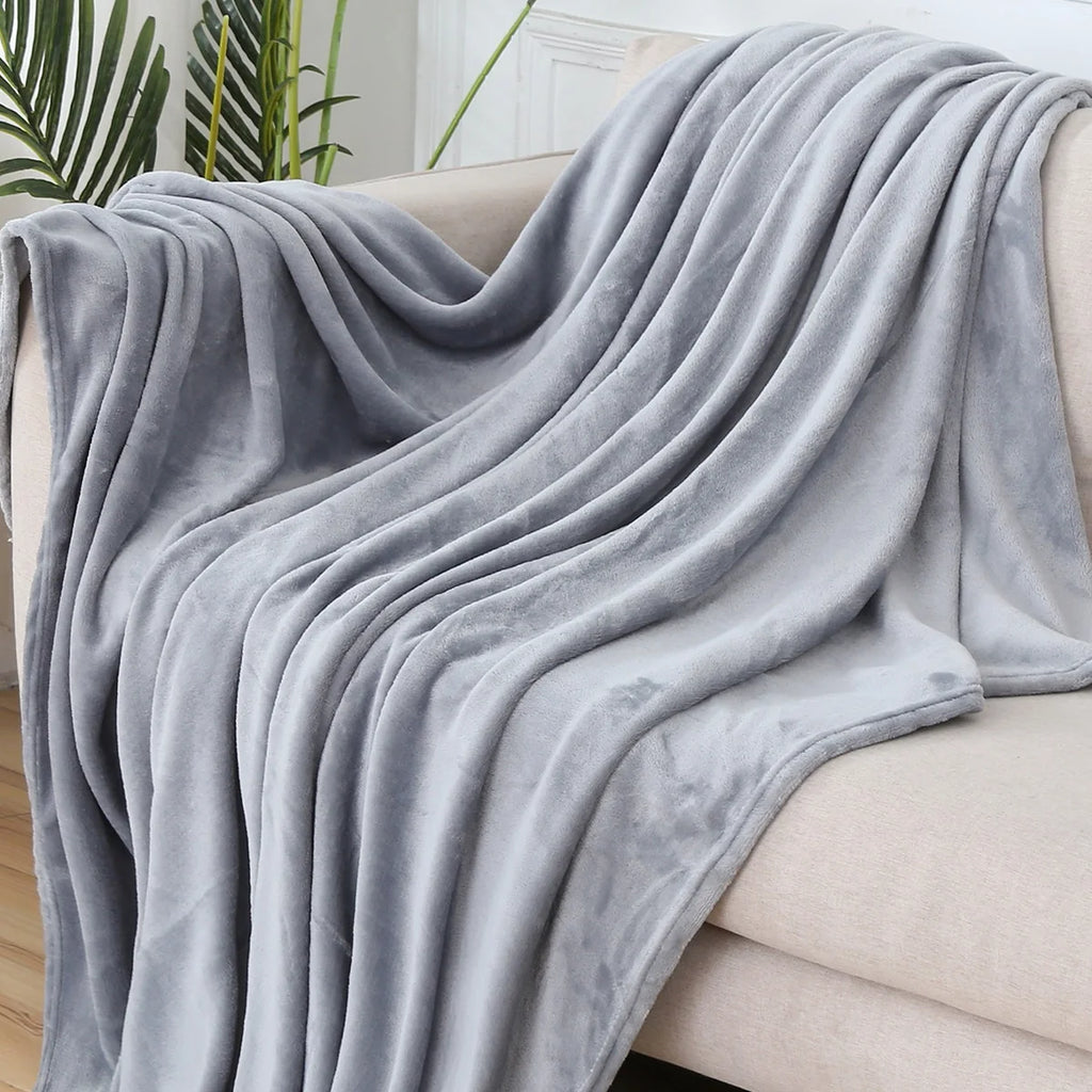 Plaid polaire uni gris clair drapé sur un canapé crème