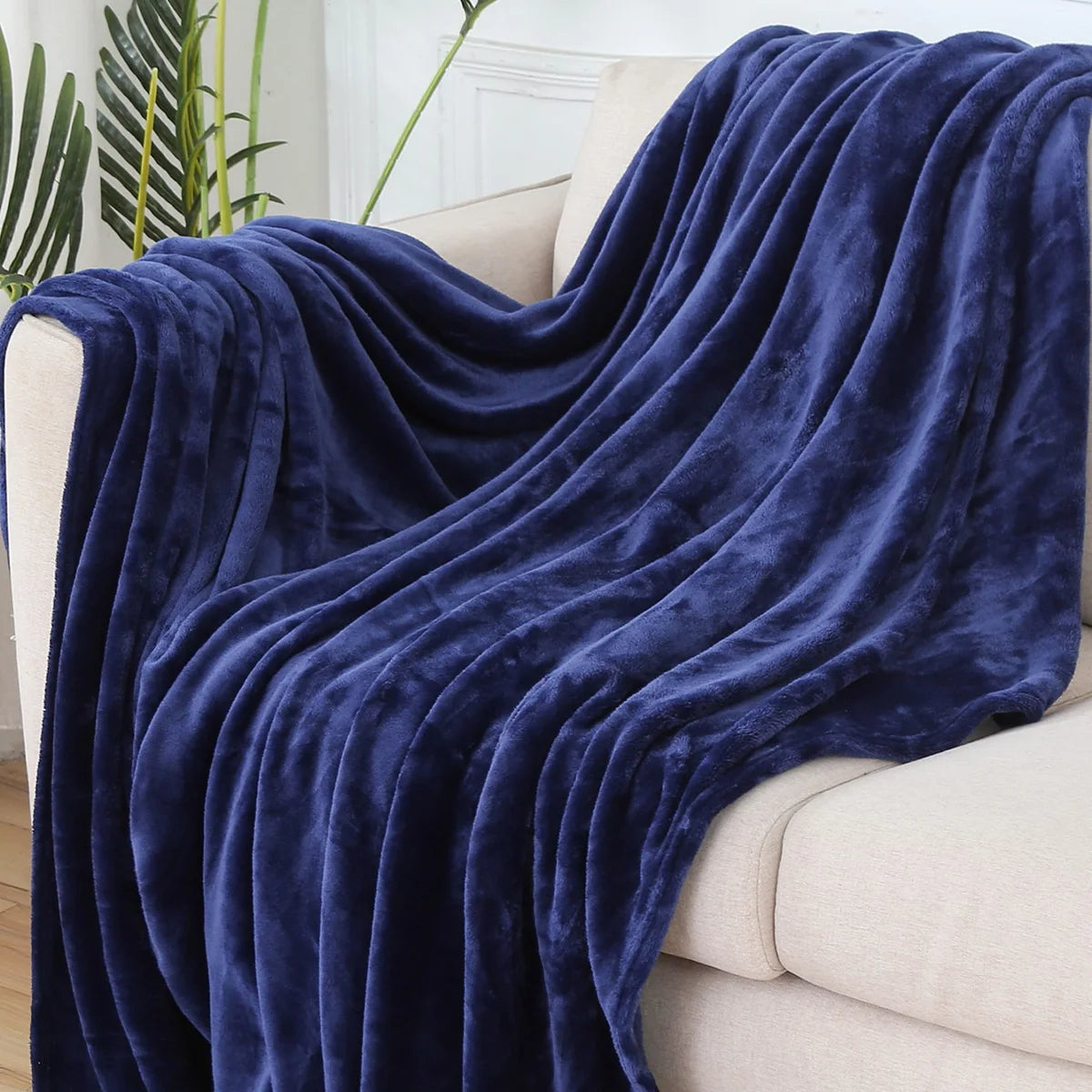 Plaid polaire uni bleu nuit drapé sur un canapé crème