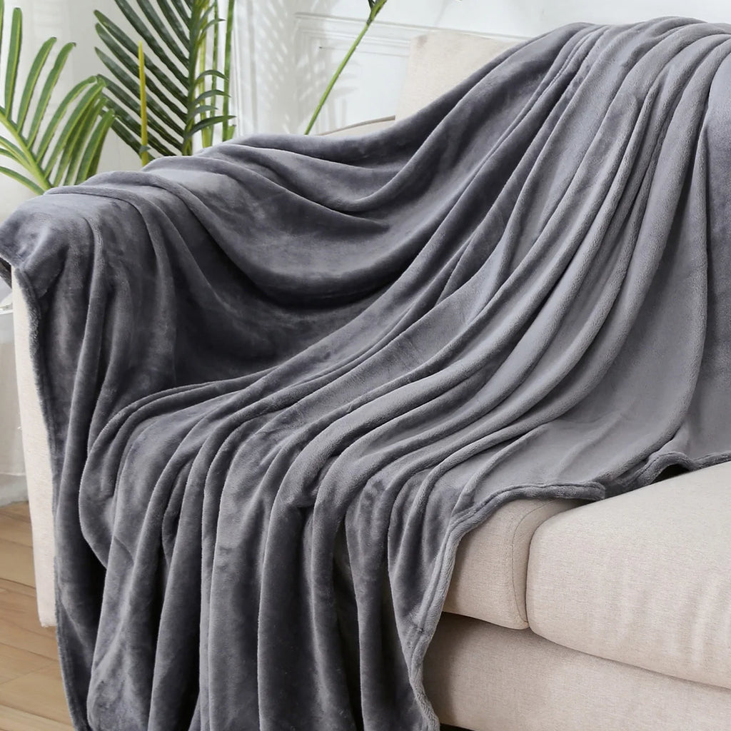 Plaid polaire uni gris foncé drapé sur un canapé crème