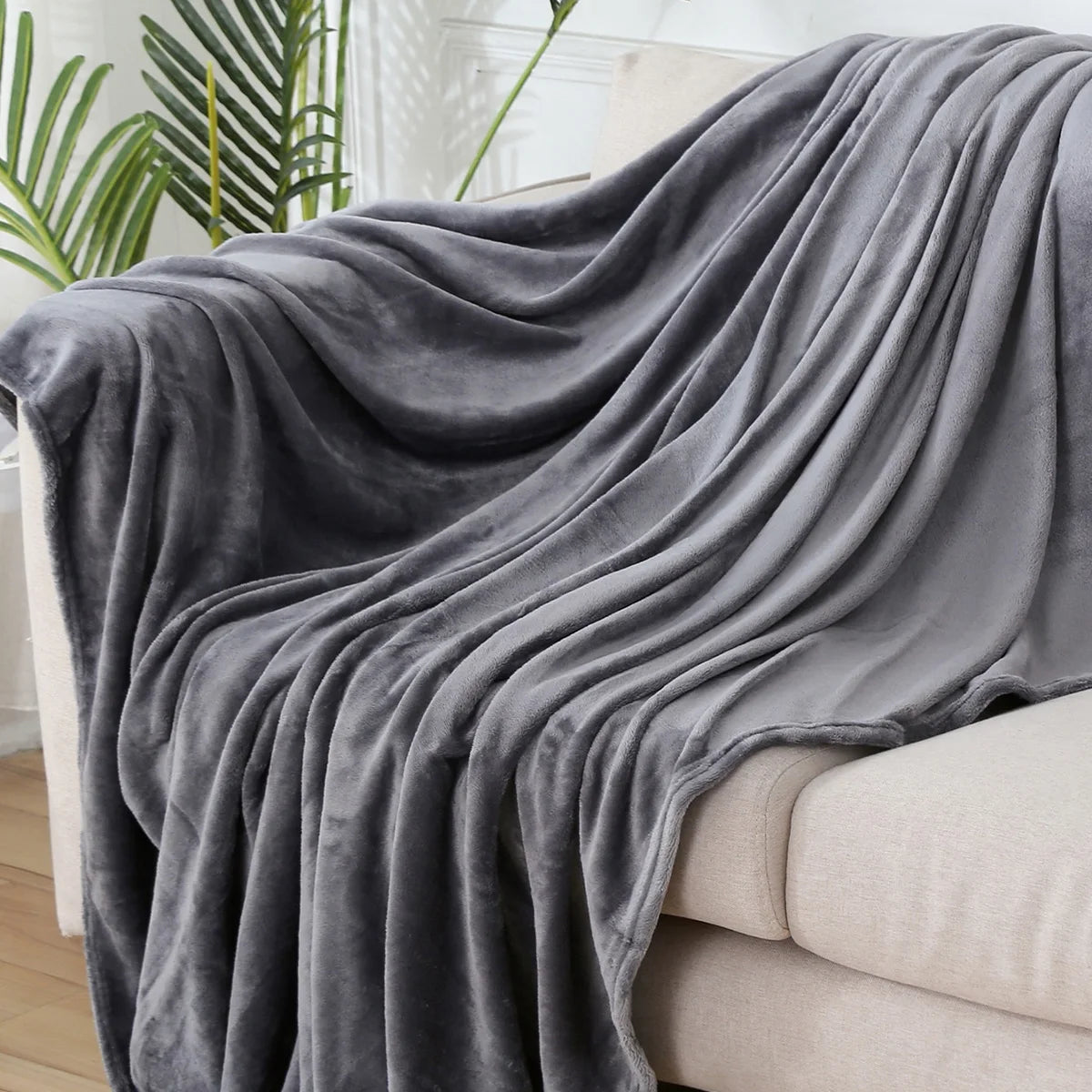 Plaid polaire uni gris foncé drapé sur un canapé crème