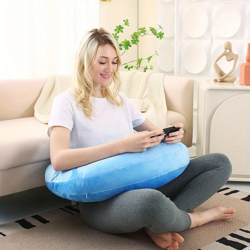 Coussin de lecture en C bleu ciel autour d’une femme assise par terre qui joue à la console