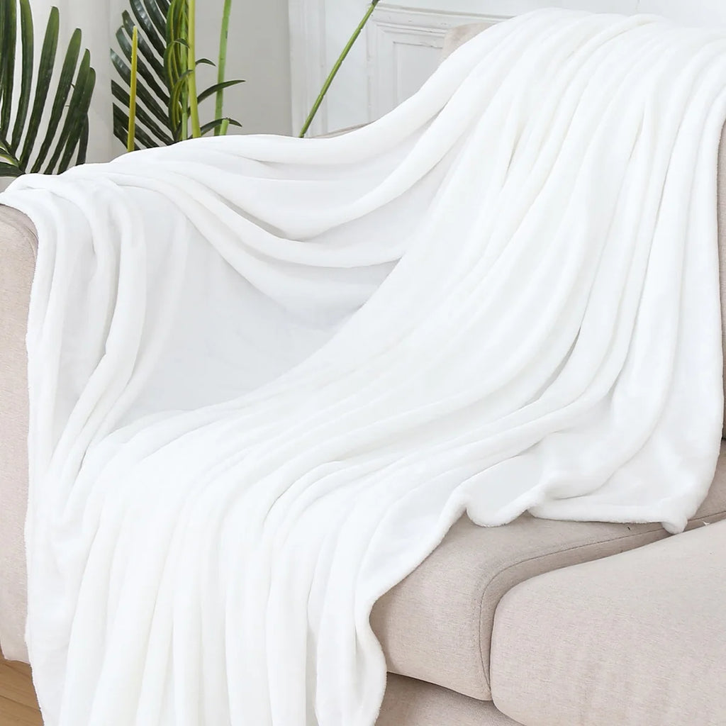 Plaid polaire uni blanc drapé sur un canapé crème