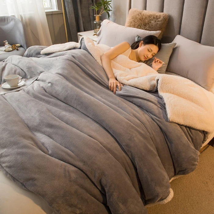 Plaid sherpa double face gris perle sur un lit